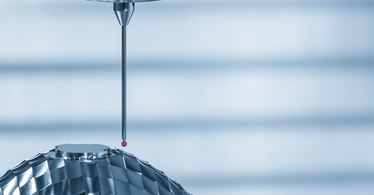 A close-up of a styli with a stainless steel stem. The styli is hovering above a metal part with many divots.