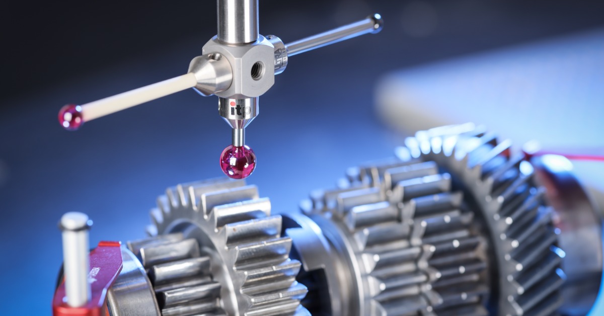 A measurement stylus positioned above a silver gear assembly with pink tips, blue lighting, and red fixture pieces.
