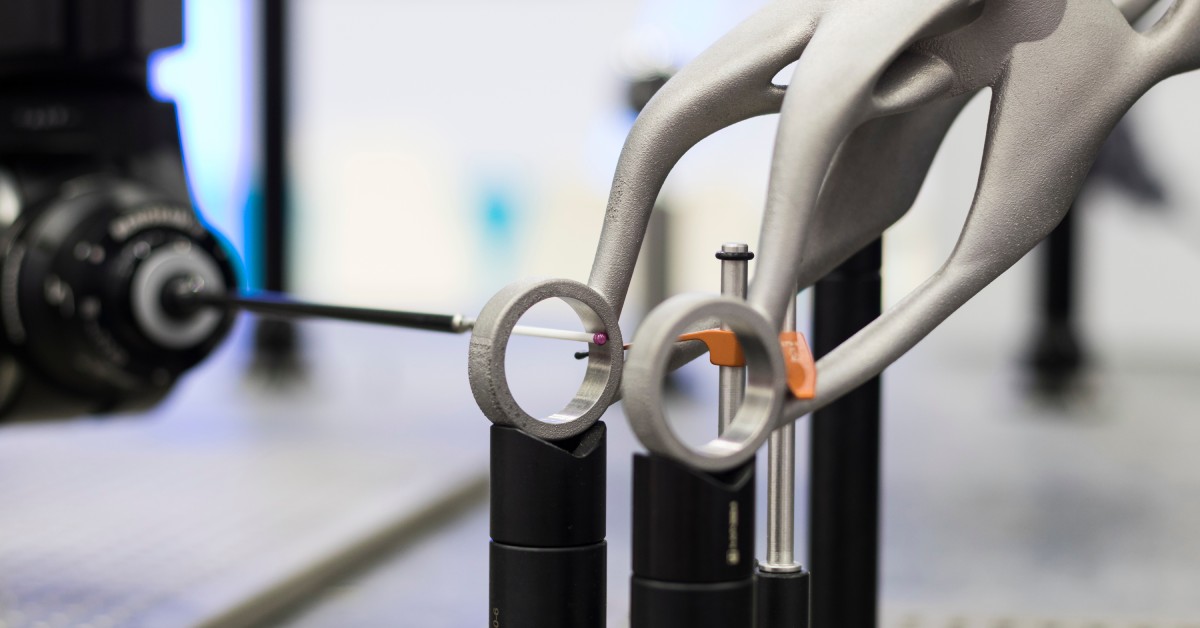 A CMM machine and stylus measure the dimensions of an object. The object is metal and the stylus moves along a ring in the item.